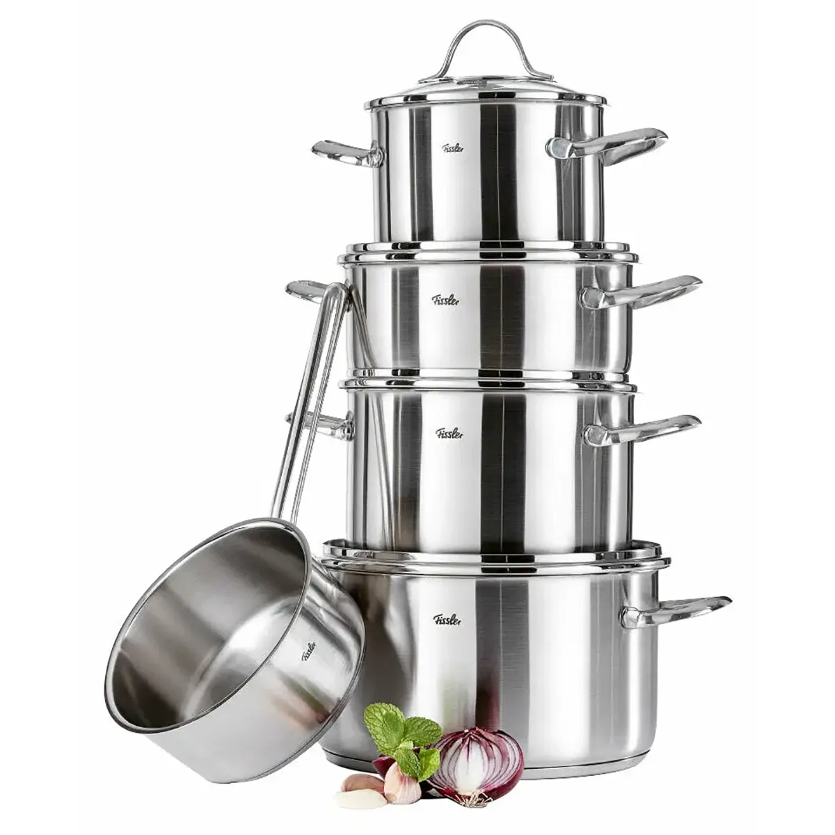Das Fissler Topf-Set PARIS 5-teilig von Fissler aus Edelstahl ist gestapelt mit Deckeln arrangiert, daneben stehen eine induktionsgeeignete Stielkasserolle sowie Zwiebel, Knoblauch und Minze.