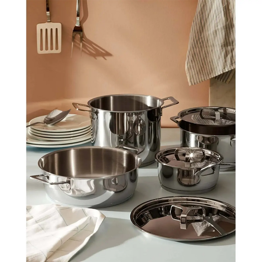 Das Alessi AJM100S9 9er-Set Stahltöpfe in silber, induktionsgeeignet, steht auf einer Küchentheke mit an der Wand hängenden Utensilien.