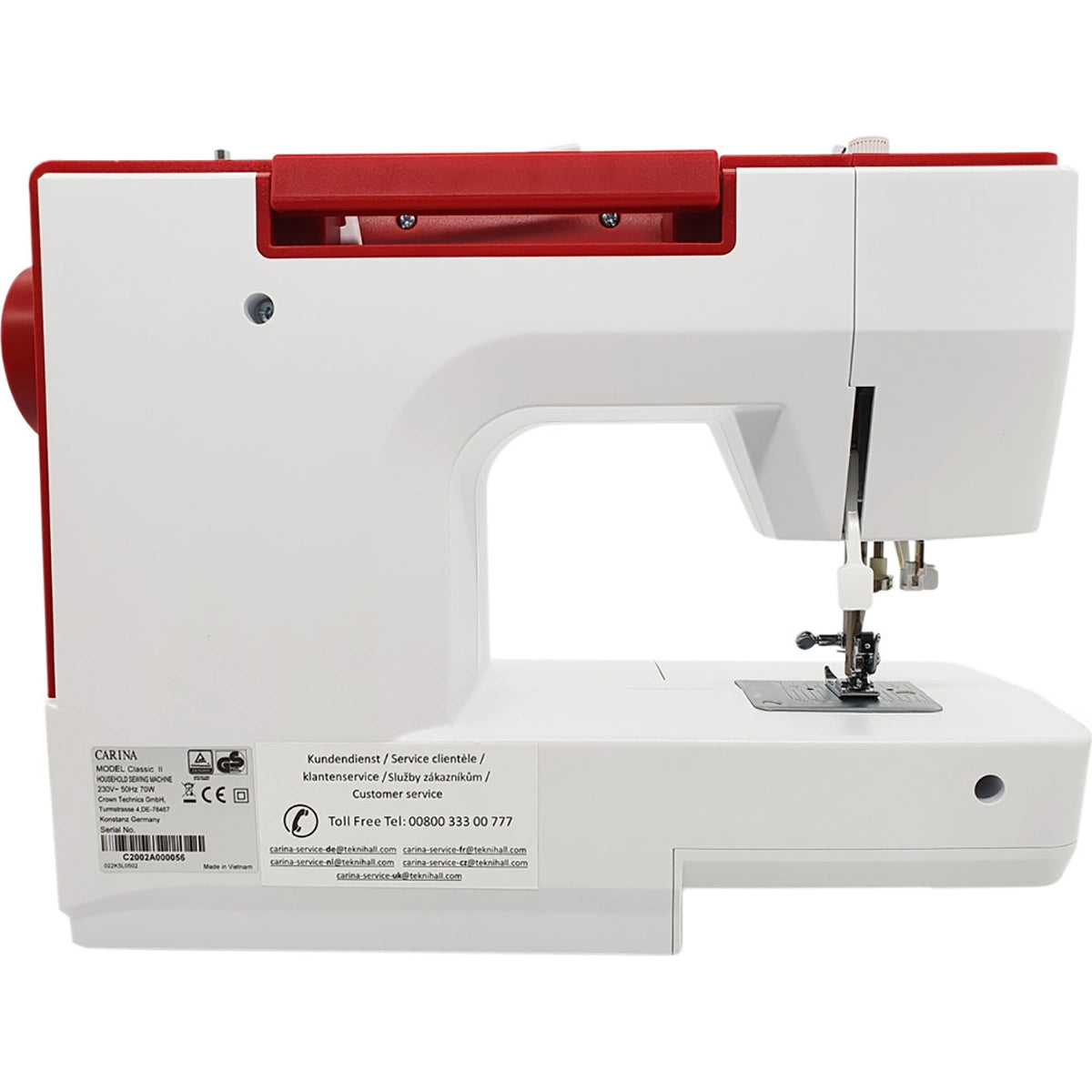 Eine weiß-rote CARINA Classic II Freiarm-Nähmaschine von CARINA wird von der Seite gezeigt, wobei der Nadelbereich, der Nähfuß, der Spulenstift und die Bedienknöpfe hervorgehoben werden. Auf der unteren linken Seite der Maschine sind Aufkleber und Serviceinformationen zu sehen.