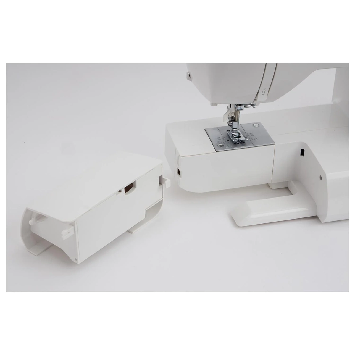 Eine Nahaufnahme der SINGER Nähmaschine "660L Serenade" von SINGER, mit herausgenommenem Zubehörfach und daneben auf einer weißen Fläche.