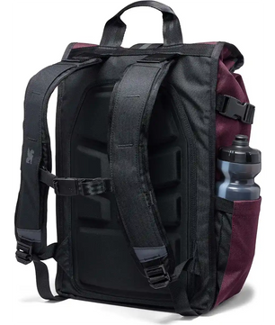 Der Chrome Barrage Rucksack - lila, hier von hinten mit gepolsterten Trägern und einer Wasserflasche in der Seitentasche, bietet ein urbanes Design, das ideal für Stadtabenteuer ist.
