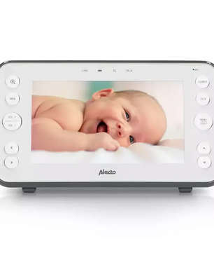 Das Alecto DVM-150 Babyphone von Alecto in Weiß mit Nachtsicht zeigt einen lächelnden Säugling, der auf einer weißen Fläche liegt.