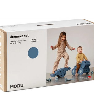 Schachtel mit MODU Spielcenter Dreamer-Set - XXL von MODU, mit zwei Kindern, die mit großen blauen Schaumstoffblöcken spielen - ideales Balance-Spielzeug zur Förderung motorischer Fähigkeiten.