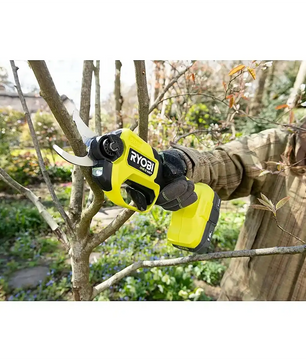 Eine Person benutzt eine grüne Ryobi HP RY18SCXA-0 Akku-Gartenschere von Ryobi, um einen Baumast im Garten zu schneiden.