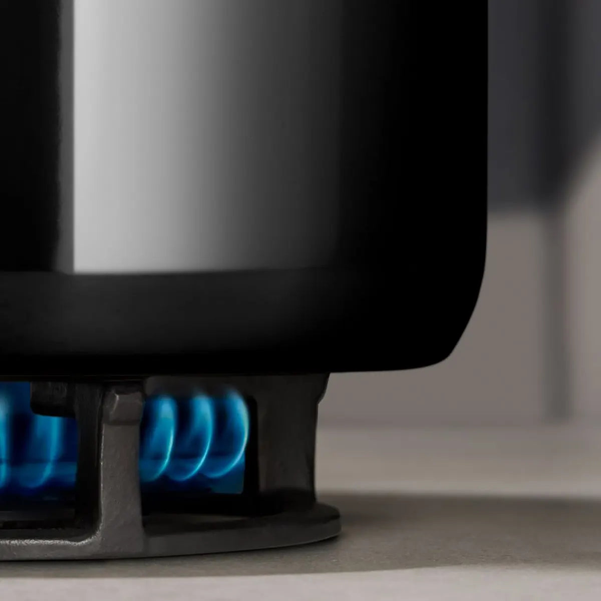 Nahaufnahme eines schwarzen WMF Topfset 4-tlg. Fusiontec Essential Pro Topf auf einem Herd, der von einer blauen Gasflamme erhitzt wird. Dieses 4-teilige Set von WMF aus langlebigem Fusiontec-Material garantiert zuverlässige Leistung beim täglichen Kochen.