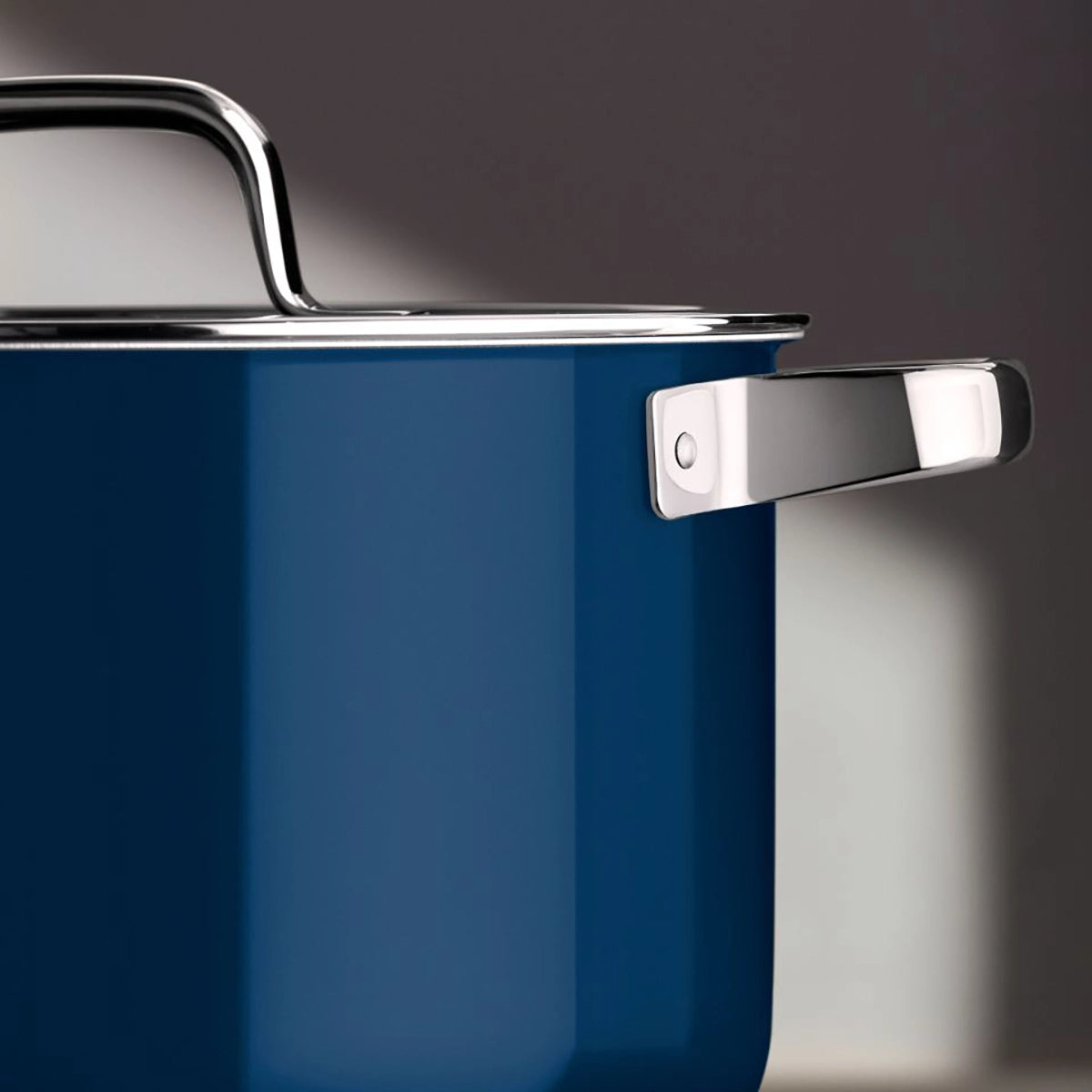 Eine Nahaufnahme des blauen WMF Fusiontec Mineral Pro Topf-Set, 4-teilig, Tim Raue Edition, mit silbern glänzenden Griffen und Deckel, vor einem unscharfen Hintergrund.