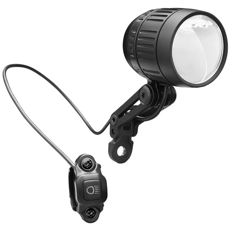 Der Busch & Müller Lumotec IQ-XM Dynamoscheinwerfer in schwarz, mit Halterung und kabelgebundenem Fernschalter, verfügt über Fernlichtfunktion und StVZO-Zulassung. Abgebildet ist er vor weißem Hintergrund.
