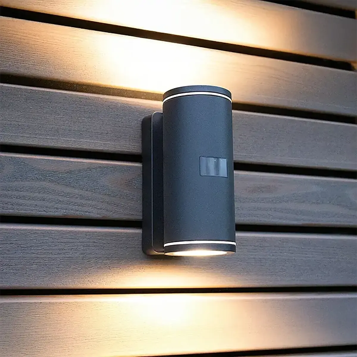 Die Steinel L 940 SC Außenwandleuchte von Steinel ist eine moderne, an der Wand montierte LED-Außenleuchte in Schwarz, die sowohl nach oben als auch nach unten auf horizontale Holzlamellen strahlt und Ihrem Außenbereich Stil und Funktionalität verleiht.
