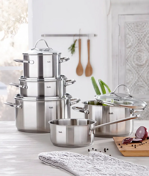 Das Fissler Topf-Set PARIS 5-teilig aus Edelstahl steht induktionstauglich auf der Küchenarbeitsplatte - daneben frisches Gemüse und Kochutensilien.