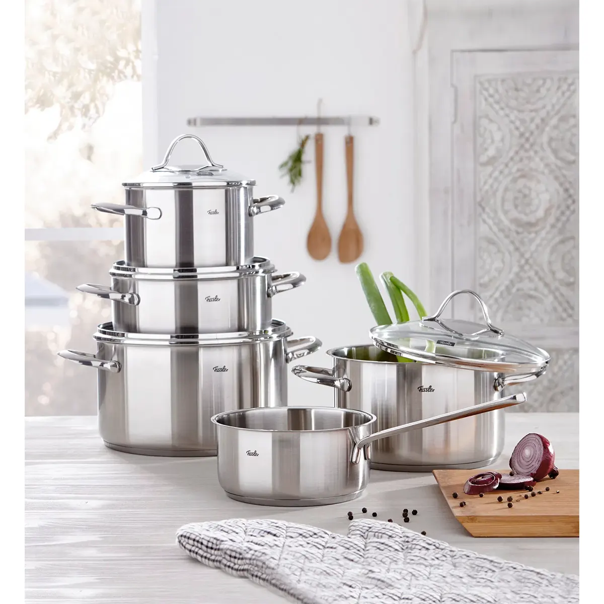 Das Fissler Topf-Set PARIS 5-teilig aus Edelstahl steht induktionstauglich auf der Küchenarbeitsplatte - daneben frisches Gemüse und Kochutensilien.