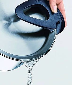 Eine Hand gießt Wasser durch den eingebauten Siebdeckel eines Fissler Topfset Intensa 5-tlg. matt-praktisch und induktionsgeeignet.