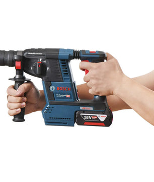 Hände halten den Bosch Professional GBH 18V-26 F Akku-Bohrhammer in blau von Bosch vor einem weißen Hintergrund.