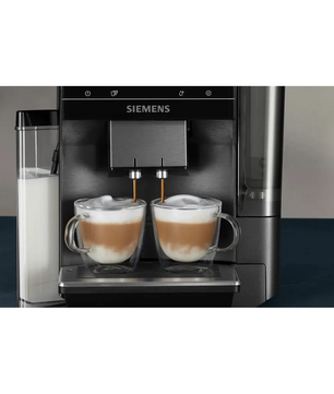 Ein Siemens EQ700 Integral TQ717DF5 Kaffeevollautomat – grau von Siemens, der zwei Cappuccinos mit sichtbarem Milchschaum zubereitet, serviert in Glasbechern.