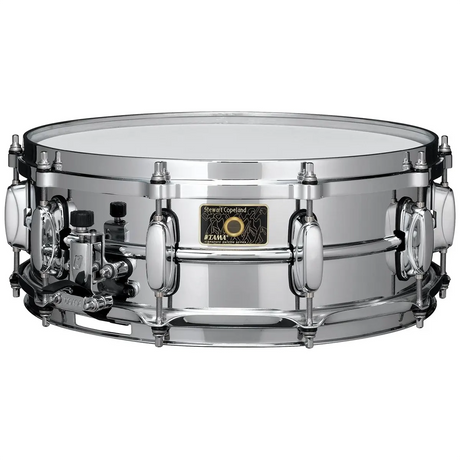 Die Tama Stewart Copeland SD 14x5 Snare Drum in silber hat verchromte Hardware, einen Messingkessel und einen Aufkleber mit der Aufschrift Stewart Copeland.