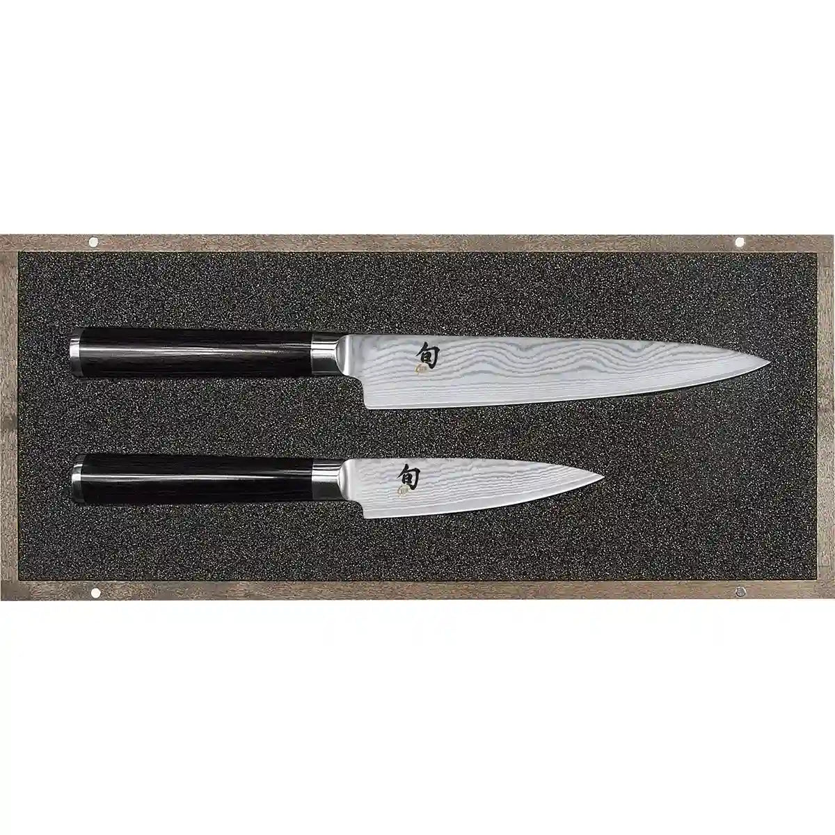 Zwei KAI DMS-200 Shun Tranchierset-Messer mit schwarzen Griffen liegen auf einer mit Schaumstoff ausgekleideten Ausstellungsplatte.