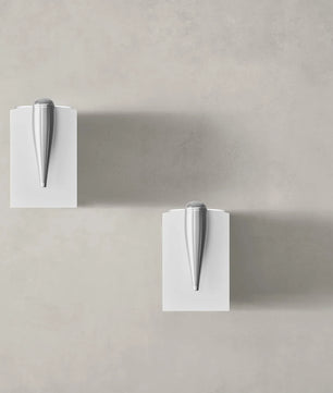 Zwei moderne silberne Türgriffe auf weißen quadratischen Platten vor einer hellgrauen Wand, die das raffinierte Design des Bowers & Wilkins 705 S3 Regallautsprecher - Paar Satin Weiß widerspiegeln.