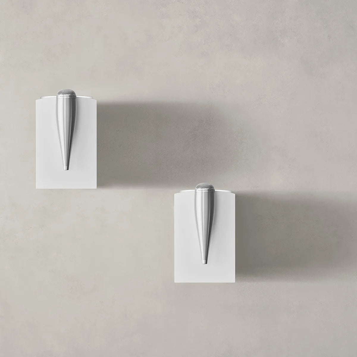 Zwei moderne silberne Türgriffe auf weißen quadratischen Platten vor einer hellgrauen Wand, die das raffinierte Design des Bowers & Wilkins 705 S3 Regallautsprecher - Paar Satin Weiß widerspiegeln.