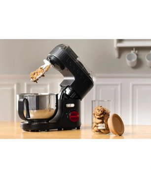 Die Bodum Bistro 11381 Küchenmaschine in Schwarz mit starkem 700-Watt-Motor steht im Retro-Design auf der Arbeitsplatte neben einem Glas Cookies, während frischer Keksteig am Aufsatz haftet.