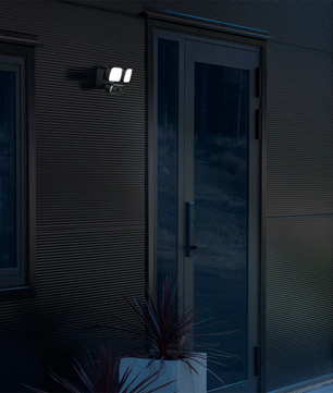 Eine moderne Außentür bei Nacht, beleuchtet von der Konstsmide Smartlight 7869-750 Kameraleuchte in schwarz, für mehr Sicherheit und Sichtbarkeit.