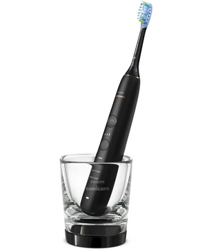 Die Philips DiamondClean 9000 HX9913/18 Schallzahnbürste in Schwarz steht aufrecht im Glas-Ladebecher - von Philips, für effektive Plaque-Entfernung und elegantes Design.