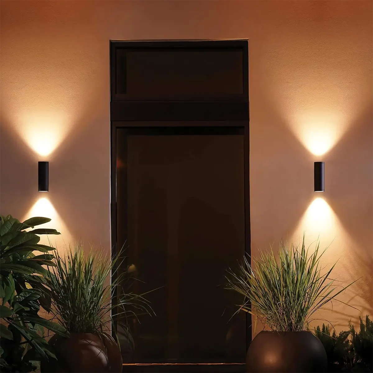 Moderner Eingangsbereich mit intelligenter Außenbeleuchtung - zwei Philips Hue Outdoor Appear Wandleuchten - Schwarz von Philips erhellen den Eingangsbereich, mit Topfpflanzen auf jeder Seite.