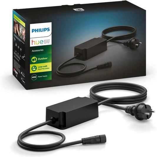 Das Philips Hue Outdoor-Netzteil – schwarz von Philips mit IP67-Zertifizierung bietet zuverlässigen Schutz vor Wasser und Staub und ist die perfekte Ergänzung für Ihr Niedervolt-Außenbeleuchtungssystem. Im Hintergrund sind das Anschlusskabel, der Stecker und die Produktverpackung zu erkennen.