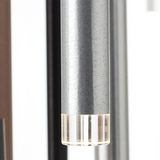 Eine Nahaufnahme der Brilliant Living Cembalo 16-flammig LED-Pendelleuchte in Braun/Kaffee, die sich durch Energieeffizienz, dimmbare Beleuchtung und eine gebürstete silberne Oberfläche mit einem transparenten, geriffelten Ende vor einem verschwommenen vertikalen Hintergrund auszeichnet.