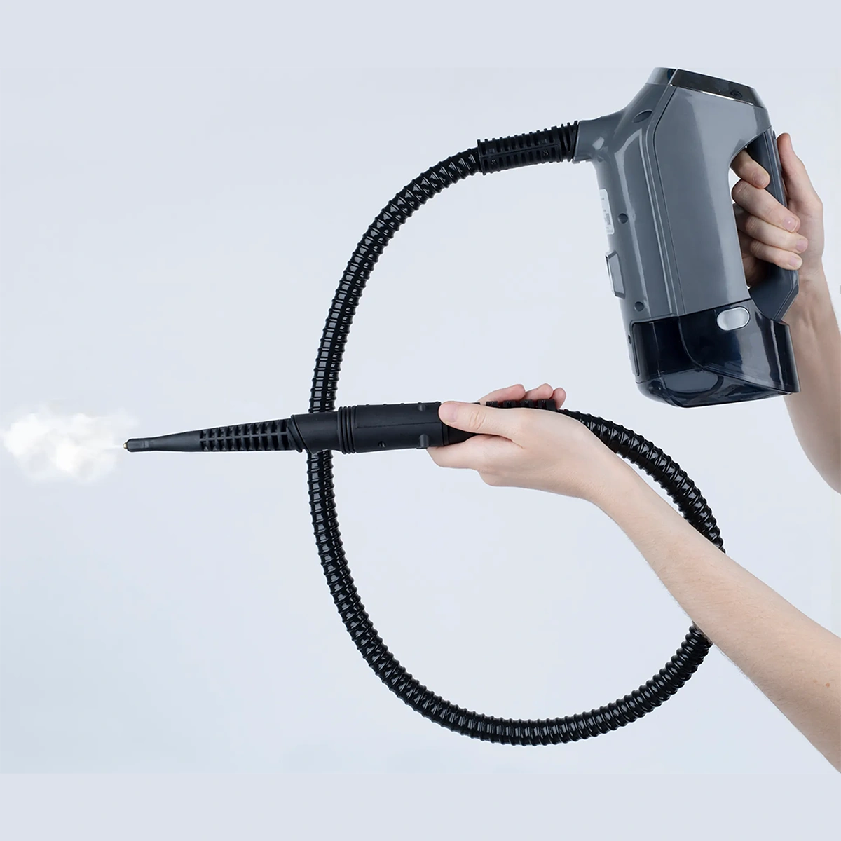 Eine Person benutzt den H.Koenig Multifunktions-Dampfstaubsauger 3 in 1 ARYA600 - grau und richtet den Dampf aus der flexiblen Schlauchdüse vor einem schlichten, hellen Hintergrund.