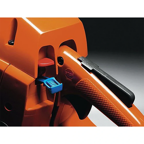 Nahaufnahme des Griffs und der Bedienelemente der orangefarbenen Husqvarna 120 Mark II (36 cm) Motorsäge. Zu sehen sind der strukturierte Griff, der schwarze Hebel sowie blaue und rote Tasten zur einfachen Bedienung und Einstellung des Werkzeugs.