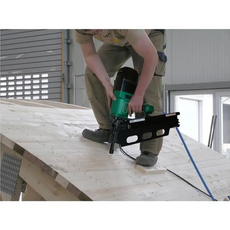 Mit dem PREBENA 10X-RK160 Druckluft-Streifennagler (100-160 mm) befestigt ein Anwender in der Werkstatt Holzbretter auf einer Dachschräge und zeigt dabei professionelles Holzbauhandwerk in PREBENA Qualität.