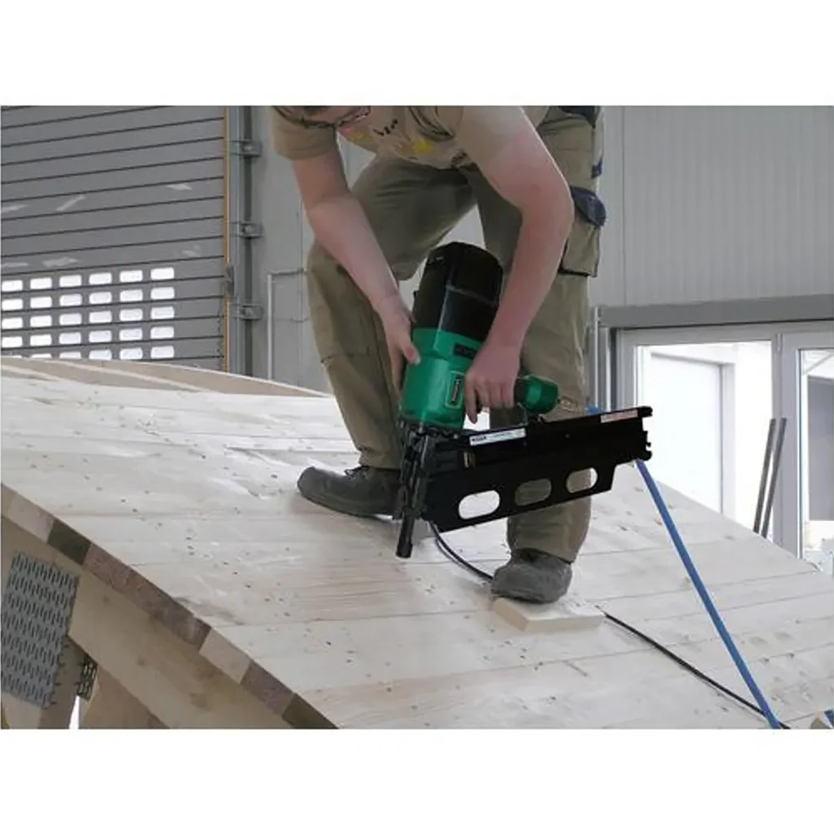 Mit dem PREBENA 10X-RK160 Druckluft-Streifennagler (100-160 mm) befestigt ein Anwender in der Werkstatt Holzbretter auf einer Dachschräge und zeigt dabei professionelles Holzbauhandwerk in PREBENA Qualität.