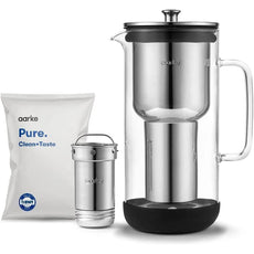 Aarke Wasserfilter Purifier aus Glas und Edelstahl mit zylindrischer Filterkartusche, separater Filterkomponente und weißem Aarke Pure Clean+Taste Nachfüllpack.