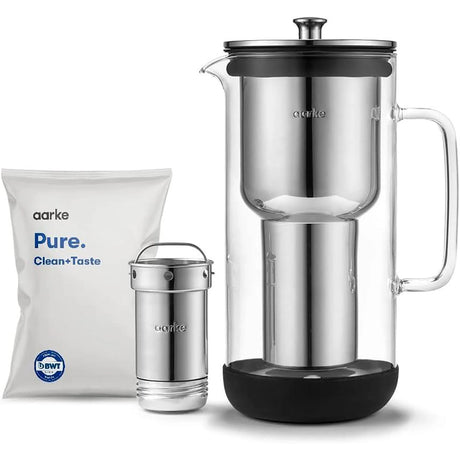 Aarke Wasserfilter Purifier aus Glas und Edelstahl mit zylindrischer Filterkartusche, separater Filterkomponente und weißem Aarke Pure Clean+Taste Nachfüllpack.