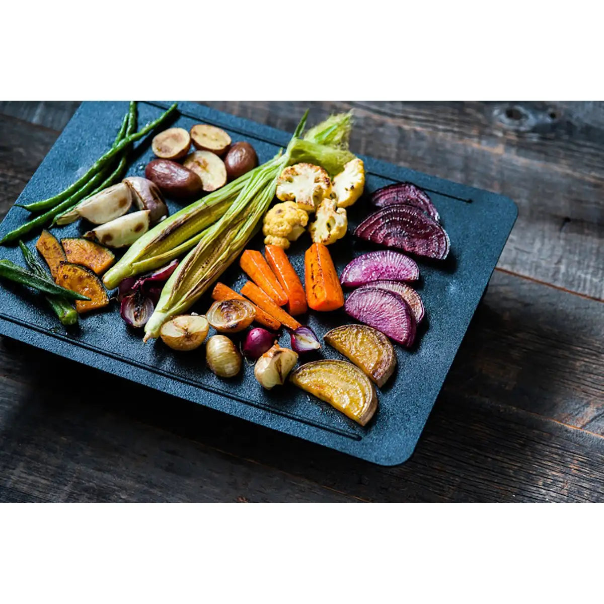 Gebratenes Gemüse wie Karotten, Kartoffeln und grüne Bohnen auf einem schwarzen Tablett - ideal zum Genießen der japanischen Esskultur oder zum Grillen mit dem abien MAGIC GRILL Elektrogrill - Schwarz von abien.