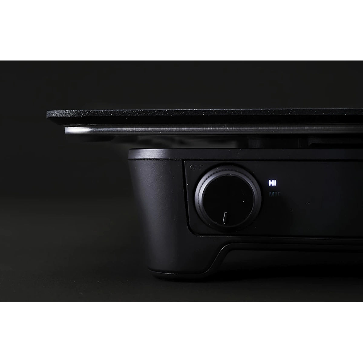 Nahaufnahme des abien MAGIC GRILL Elektrogrills in Schwarz von abien mit Einschaltknopf, Kontrollleuchte und Teppanyaki-Platte vor einem dunklen Hintergrund.