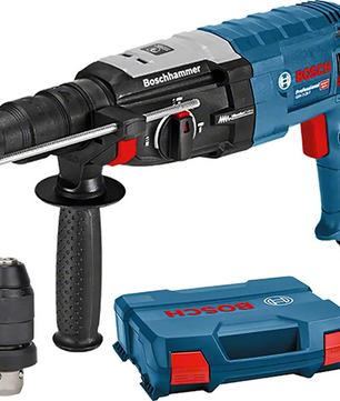 Ein blau-schwarzer Bosch Professional GBH 2-28 F Bohrhammer mit seitlichem Griff, zusätzlichem SDS-plus Bohrfutter und einem blauen Bosch-Koffer daneben.