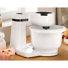 Auf dem Tresen steht die Bosch BOSCH Küchenmaschine - MUMS2AW01 in Weiß mit einer geräumigen Schüssel und einem fortschrittlichen 3D PlanetaryMixing für perfekte Mixergebnisse.