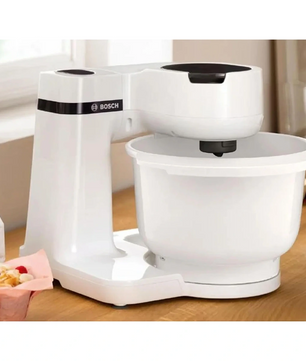 Auf dem Tresen steht die Bosch BOSCH Küchenmaschine - MUMS2AW01 in Weiß mit einer geräumigen Schüssel und einem fortschrittlichen 3D PlanetaryMixing für perfekte Mixergebnisse.