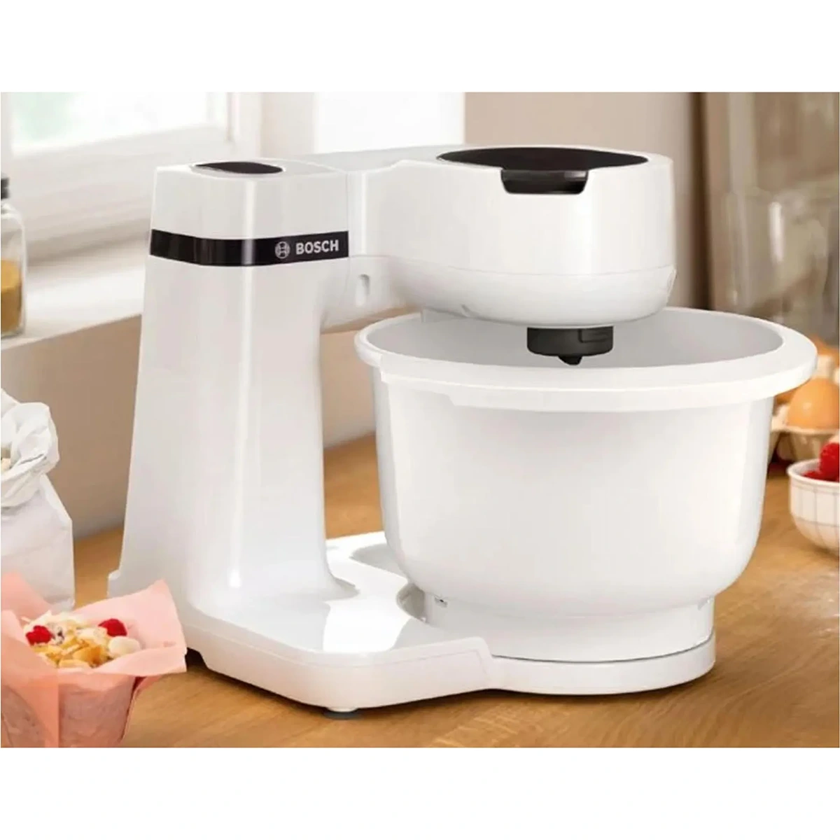 Auf dem Tresen steht die Bosch BOSCH Küchenmaschine - MUMS2AW01 in Weiß mit einer geräumigen Schüssel und einem fortschrittlichen 3D PlanetaryMixing für perfekte Mixergebnisse.