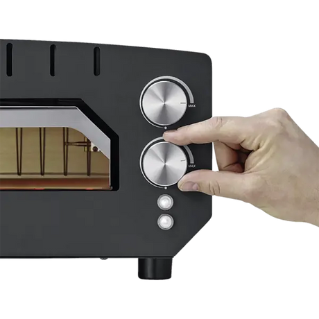 Eine Hand dreht den Drehknopf am schwarzen CASO 2249 PizzaChef 400° Pizza-Ofen mit zwei silbernen Drehreglern für Ober-/Unterhitze und Kontrollleuchten.
