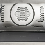 Nahaufnahme der CASO HCMG 25 Mikrowelle - silber interior: 25-Liter-Garraum aus Edelstahl mit sechseckigen Lüftungsschlitzen und Perforationen für die Luftzirkulation, ideal für eine verbesserte Heißluftfunktion. Die Backofentür ist unten teilweise geöffnet. Marke: CASO.