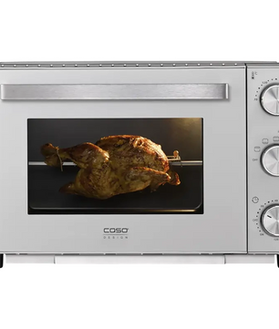 Ein ganzes Brathähnchen auf einem Grill mit Drehspieß im CASO TO 32 SilverStyle Mini-Backofen von CASO (silber) mit Drehreglern und Umluftfunktion.