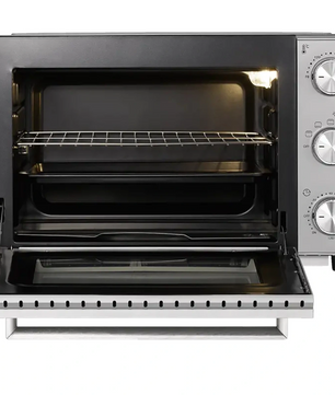 Der CASO TO 32 SilverStyle Mini-Backofen in Schwarz und Silber verfügt über einen Drahtrost, rechtsseitige Bedienknöpfe, Umluftfunktion für gleichmäßiges Backen und ist mit geöffneter Tür abgebildet.