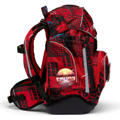 Das ergobag Pack Set (2023) AlarmBärreitschaft von ergobag ist ein rot-schwarz gemusterter ergonomischer Schulrucksack mit mehreren Reißverschlussfächern, dick gepolsterten Trägern und einem runden reflektierenden Aufnäher, der einen Sonnenuntergang über Gebäuden zeigt.