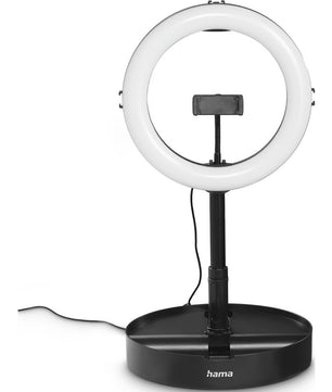 Die Hama LED-RGB-Ringleuchte SpotLight FoldUp RGB ist eine kreisförmige LED-Ringleuchte mit Telefonhalterung, montiert auf einem schwarzen, verstellbaren Ständer. Es hat ein RGB-Studio-freundliches Design, einen breiten Sockel mit dem Hama-Logo und wird mit einem Netzkabel geliefert.