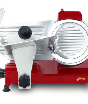 Eine rote H.Koenig Allesschneider MSX224 240 W Schneidemaschine mit kreisförmiger Klinge, einstellbarer Stärke, Lebensmittelschlitten und Schutzvorrichtung ist von vorne zu sehen. Auf dem Sockel ist das H.Koenig-Logo zu sehen.