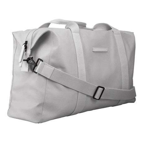 Die Horizn Studios SoFo Weekender M in Light Quartz Grey ist eine nachhaltige Reisetasche aus recycelter Baumwolle mit zwei Henkeln, einem abnehmbaren, verstellbaren Schultergurt und einer seitlichen Reißverschlusstasche, die schräg auf weißem Grund steht.