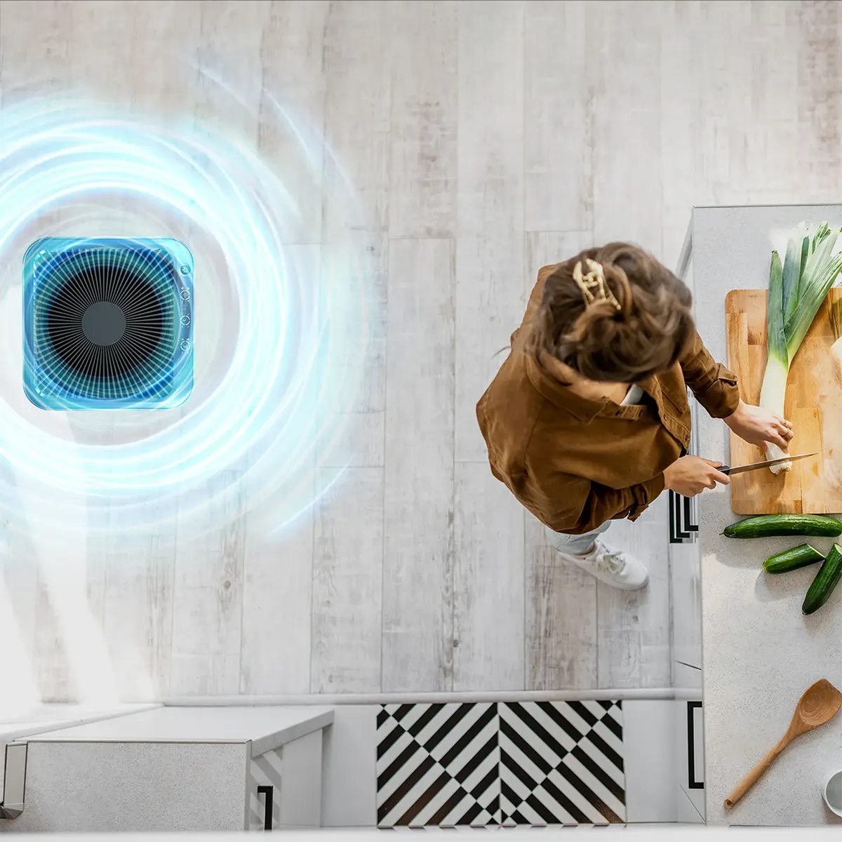 Draufsicht auf eine Frau beim Gemüseschneiden in der Küche mit dem Genius INVICTUS Air P7 Luftreiniger - Grau von INVICTUS, der mit einem leistungsstarken HEPA-13-Filter ausgestattet ist und saubere Luft in die Nähe bläst.