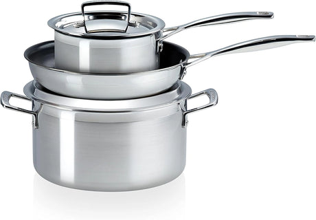 Drei Le Creuset 3 Ply Stainless Steel 3 Piece Töpfe der Marke Le Creuset sind ineinander gestapelt, ein Deckel liegt obenauf. Für Induktion geeignet.