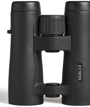 Ein Paar Noblex NF 10x42 Vector Fernglas in Schwarz mit zentralem Fokussierknopf und offenem Brückendesign, aufrecht stehend auf weißem Hintergrund. Hergestellt in Deutschland von Noblex für hervorragende Qualität und Leistung.